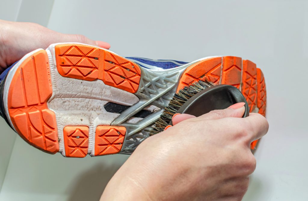 hands holding and cleaning a pair of sneakers