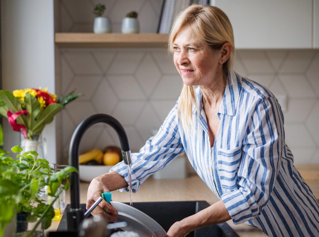 midlife woman washing dishes in a kitchen