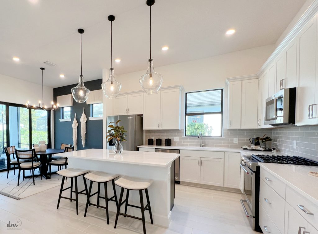 a clutter free kitchen with an island and white bar stools around it