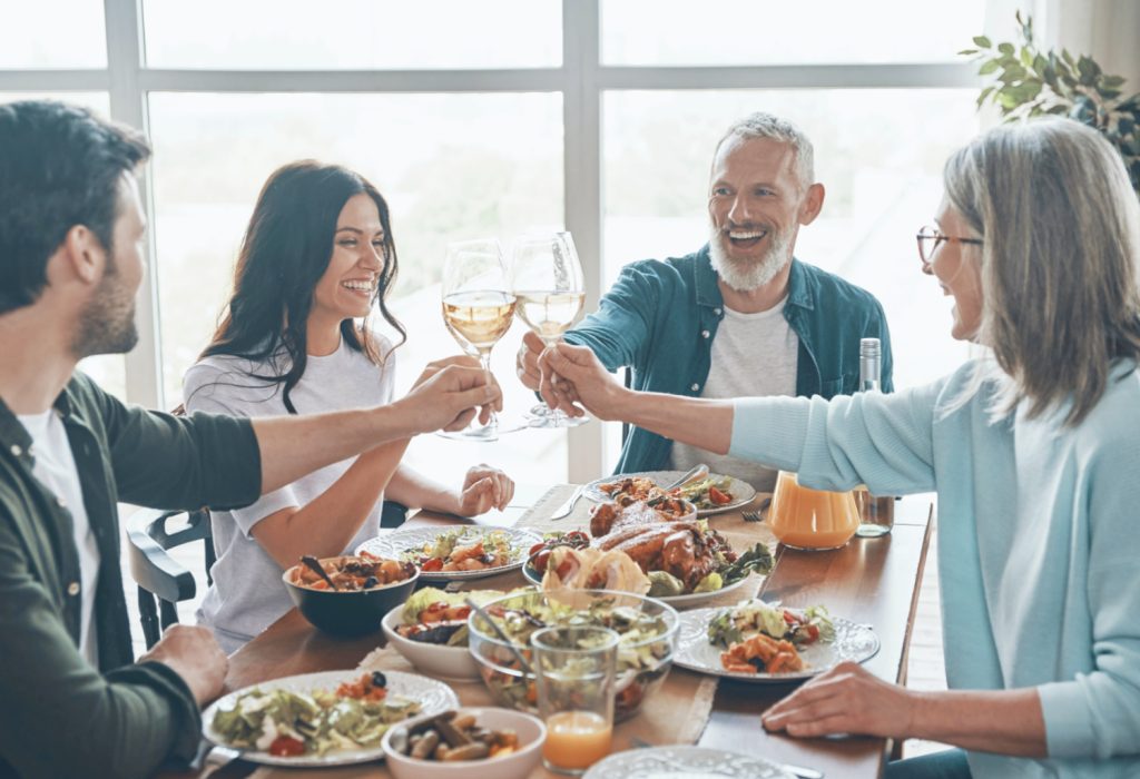 a family toasting glasses together over dinner in a home