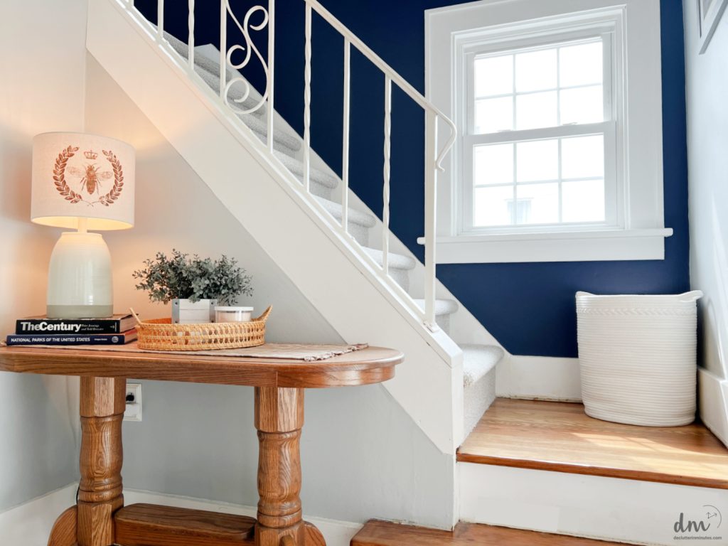 a table with lamp next to stairs and a white basket