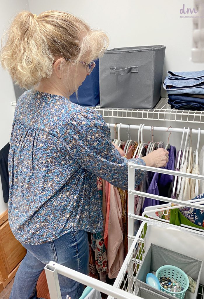 a woman flipping the direction of the hangers in her closet to be backwards
