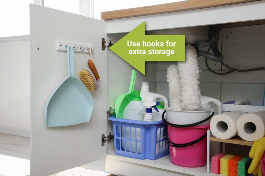 cleaning items hanging on the inside of a door under a kitchen sink
