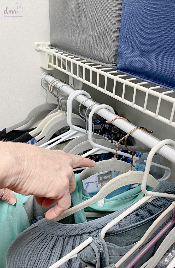 hands pointing to a hanger that is still backwards on a rod in a closet