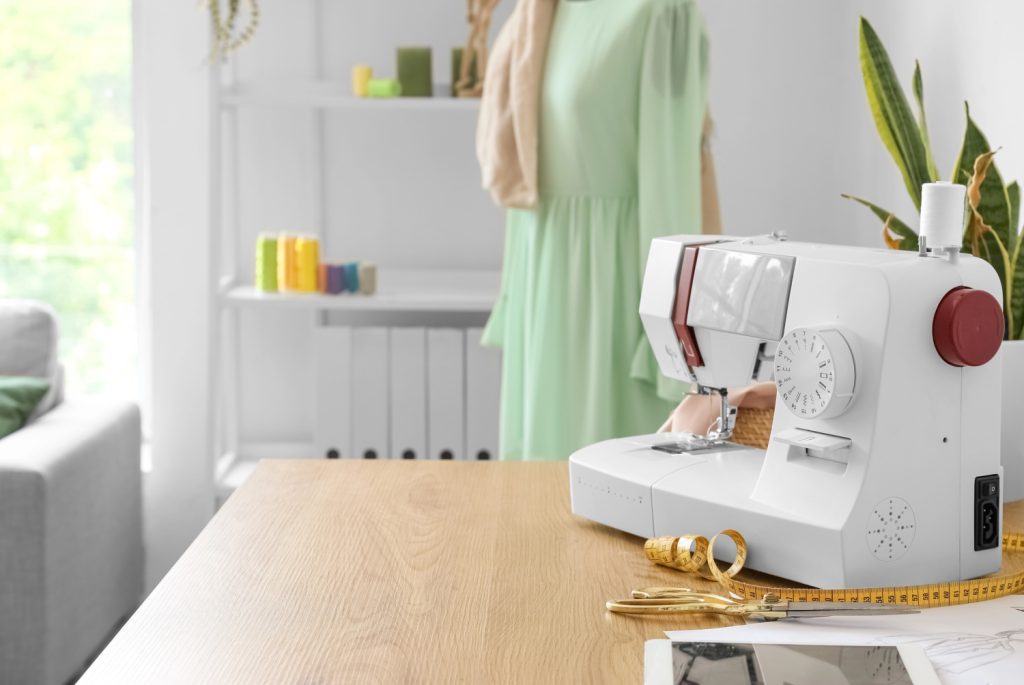 a sewing room with a machine on a table and a green dress on a form