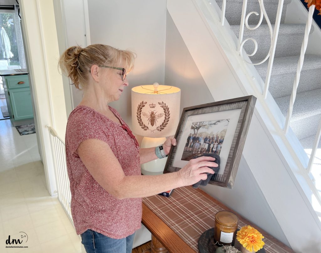 a woman dusting a family picture in a home
