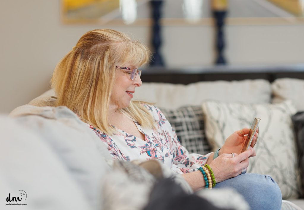 a woman smiling and looking at her phone on a couch