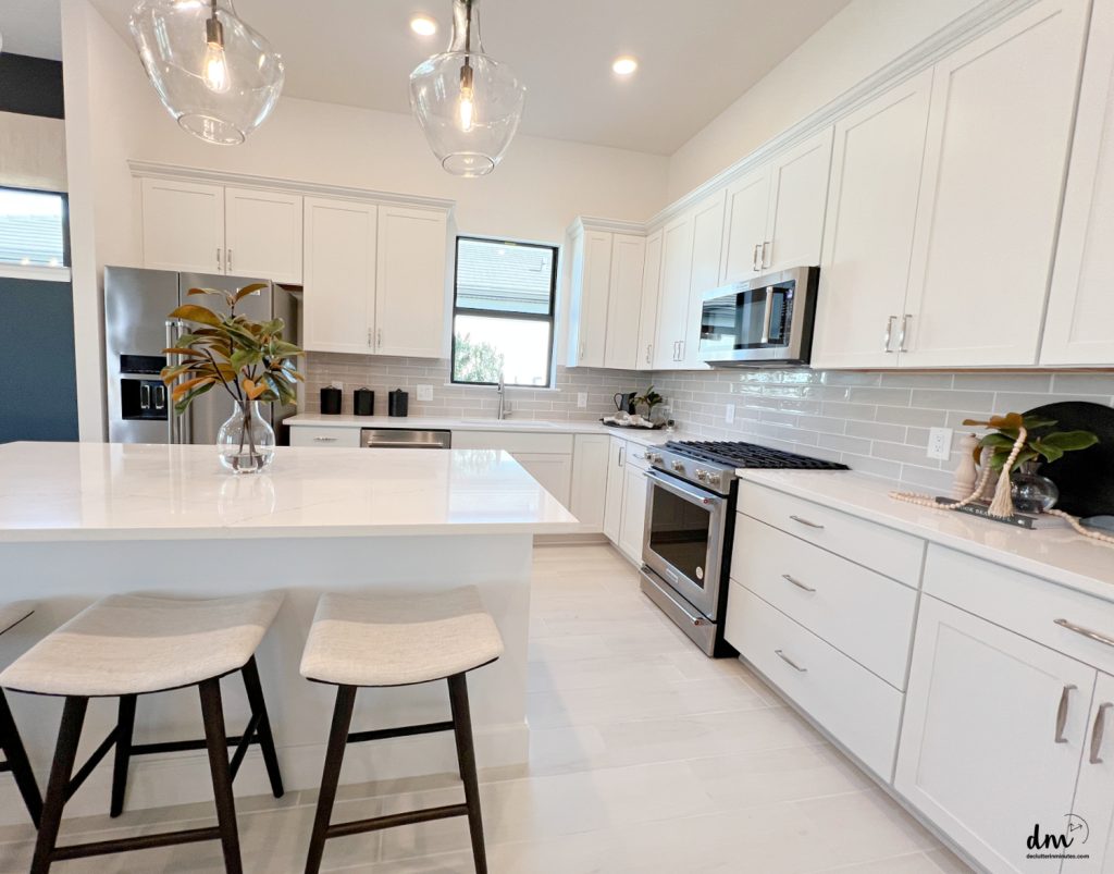 a white kitchen with steel appliances and a island with a vase