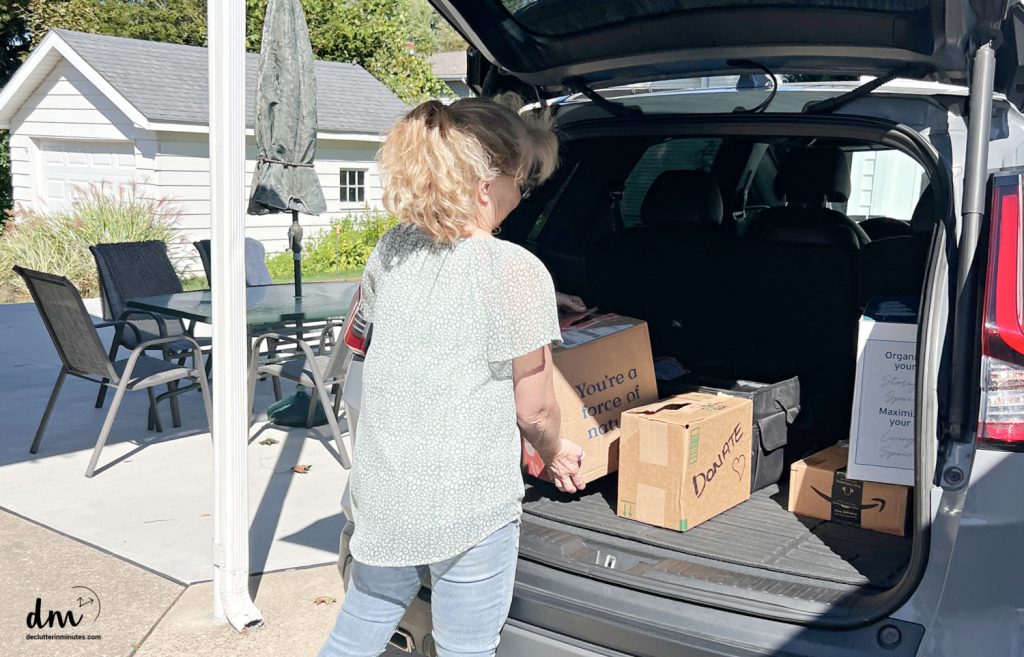 a woman putting donation boxes into the back of her car