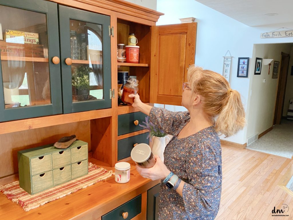 a woman sorting candles in a china cabinet