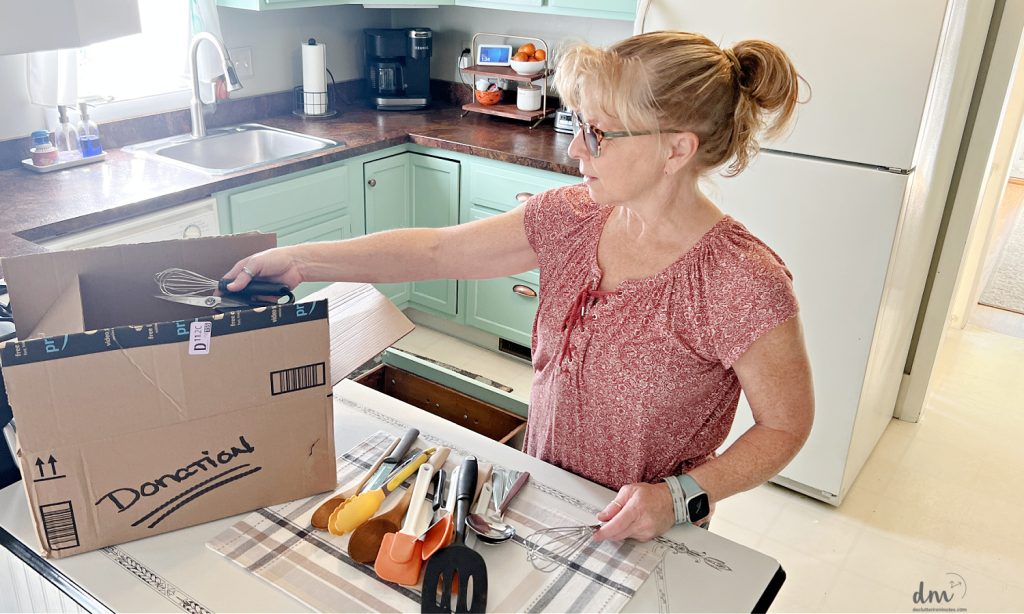 a woman sorting things into a donation box in a kitchen