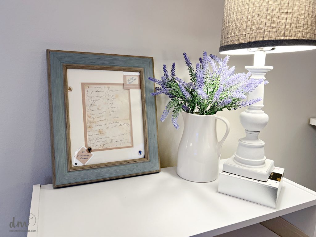 photo of an old recipe next to a white vase of flowers and a lamp
