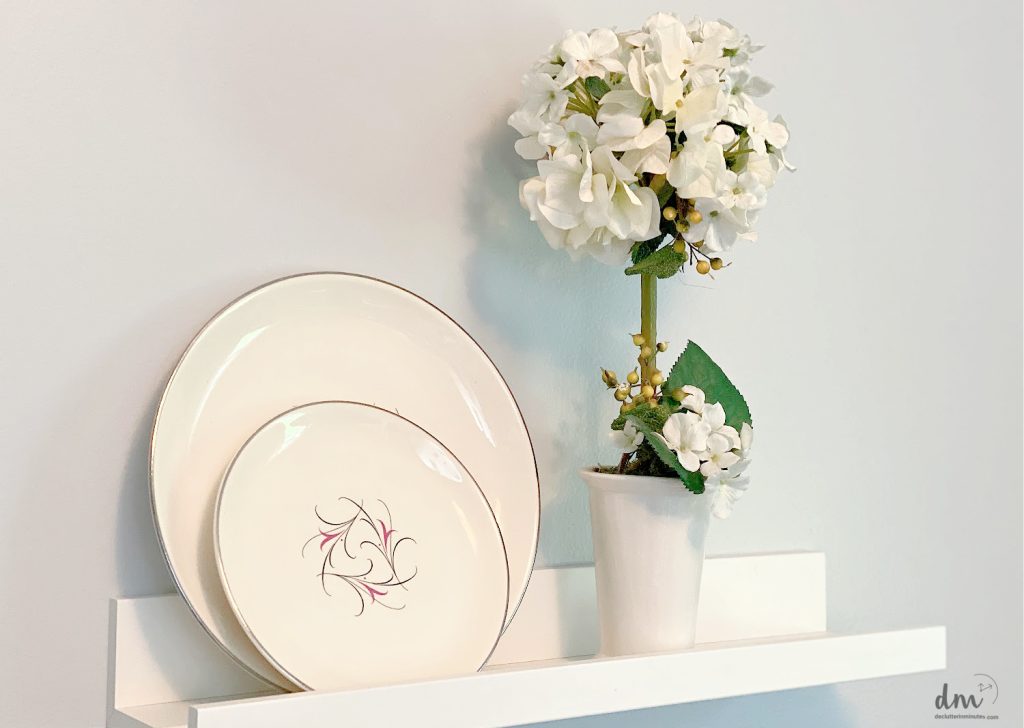 plates on a shelf next to white flowers