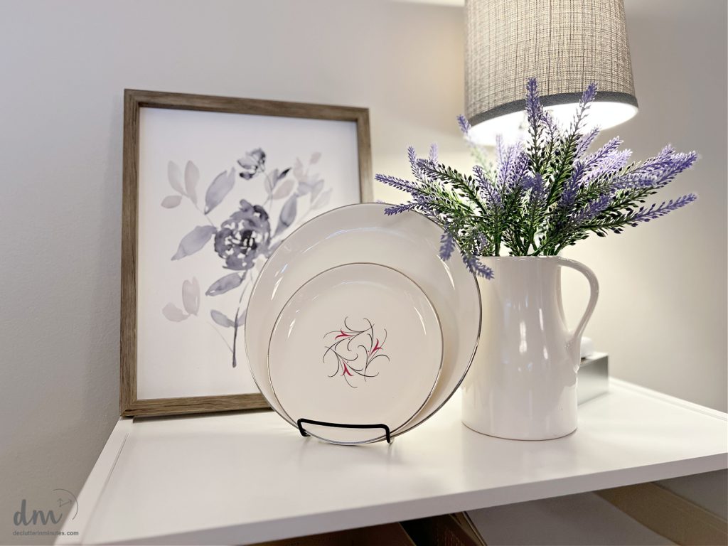 plates on a white table with purple flowers and a framed print