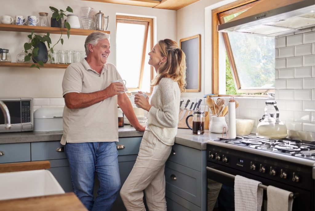 senior couple talking in kitchen drinking coffee