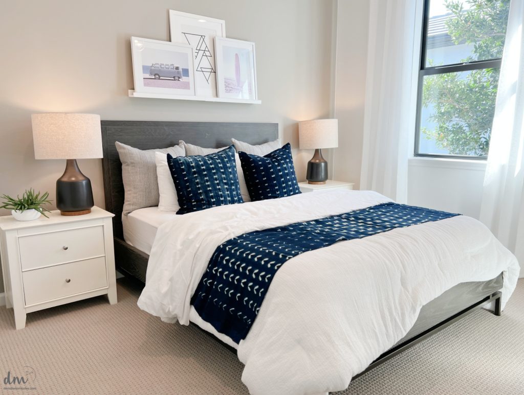 a neat bedroom with white nightstands and shelf of photos