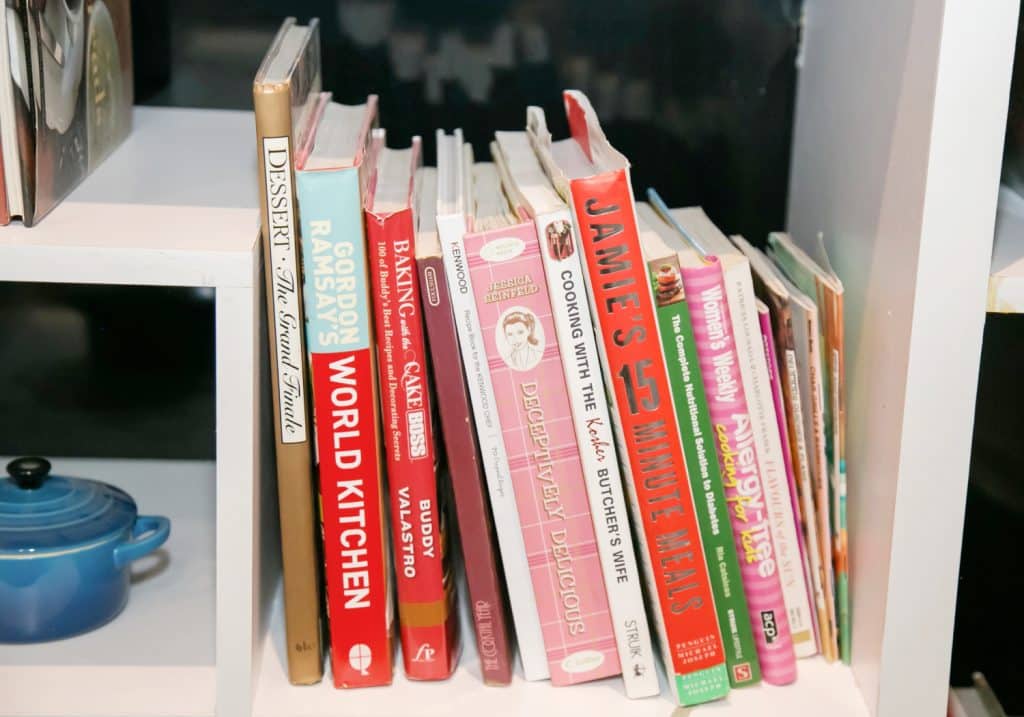 a collection of cookbooks on a white bookshelf