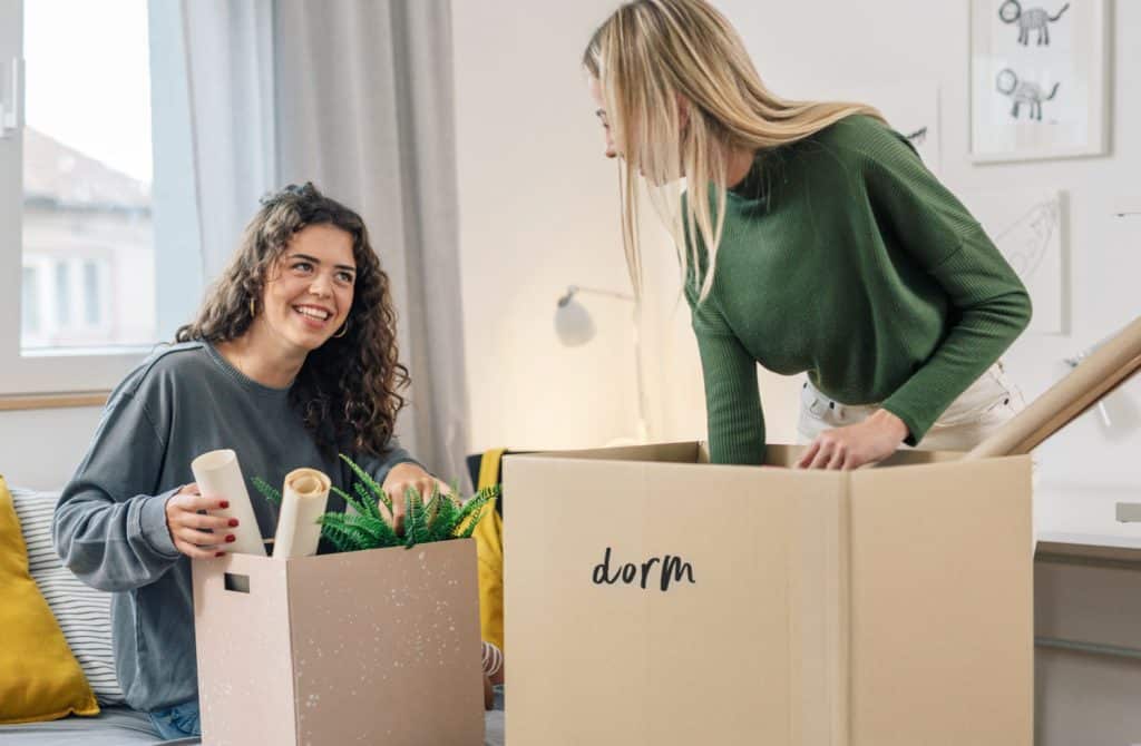 girls unpacking boxes for college in a dorm room