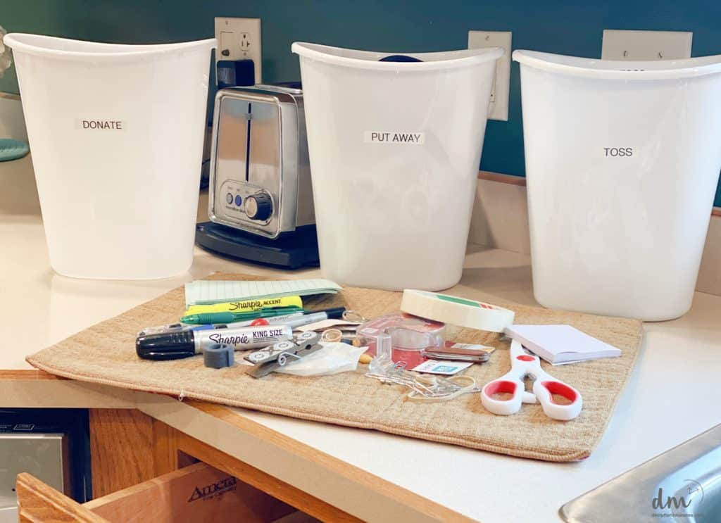 white sorting bins next to a pile of items from an opened kitchen drawer
