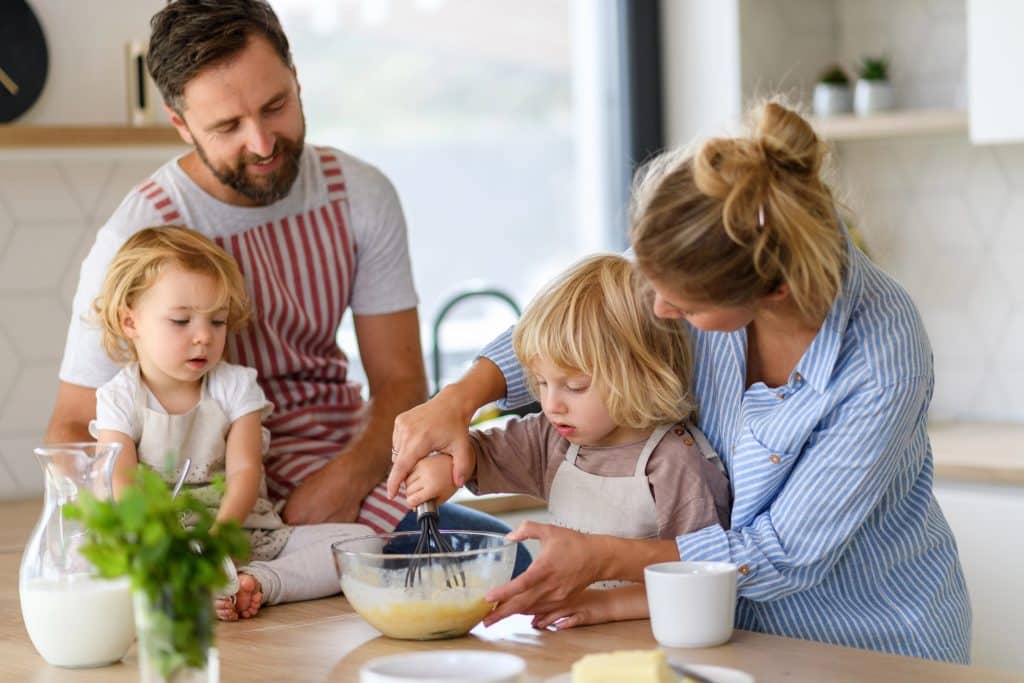 young family making pancakes together in a kitchen