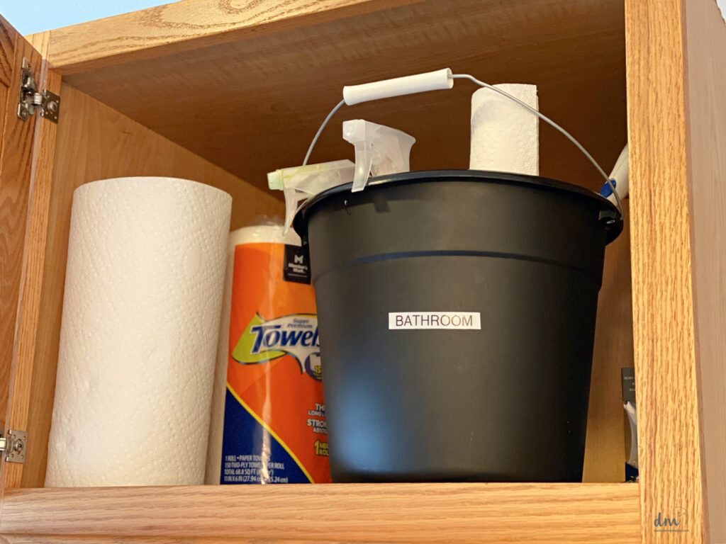 a bucket labeled Bathroom filled with cleaning supplies