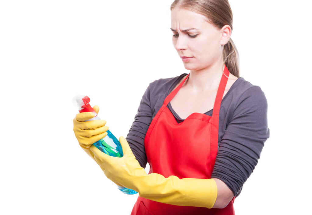 woman reading the label of a bottle of cleaner