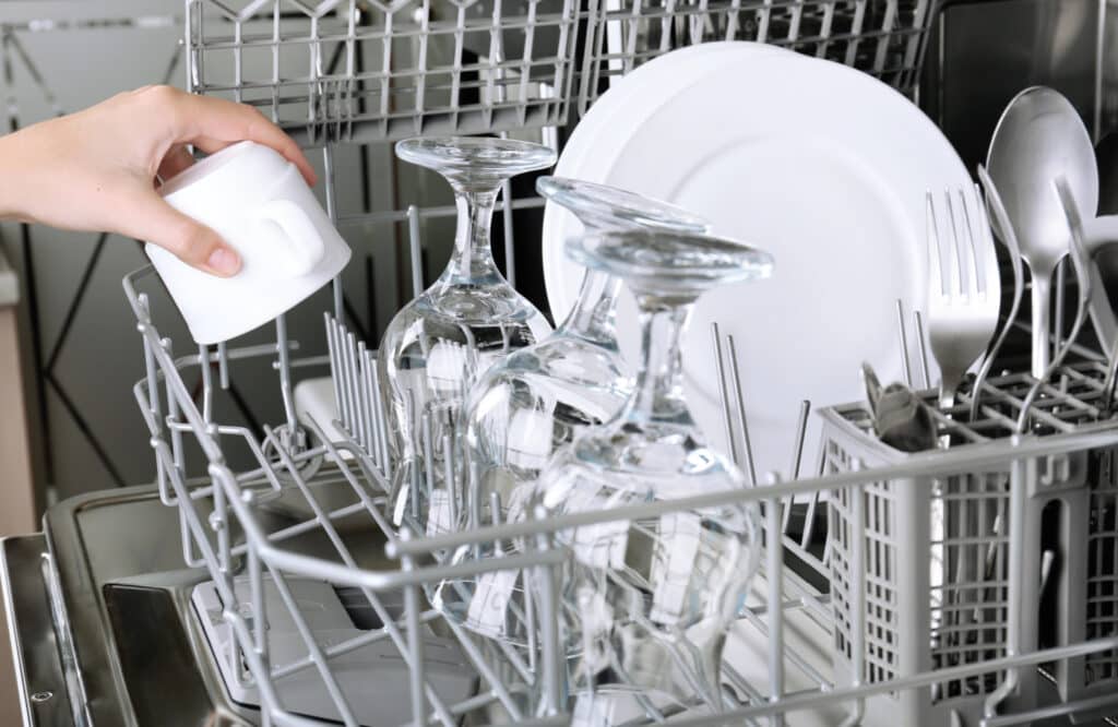 hands putting a coffee cup into a dishwasher