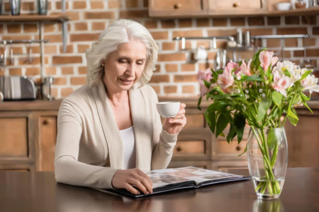 a senior woman drinking coffee looking at photos