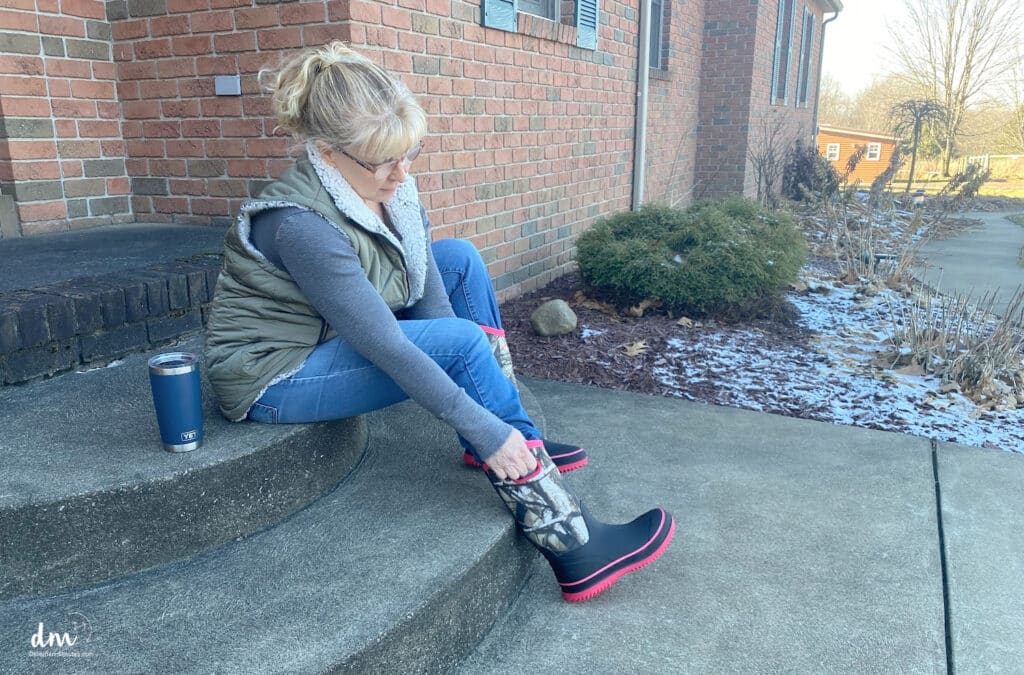 woman putting on barn boots on a front porch in the winter