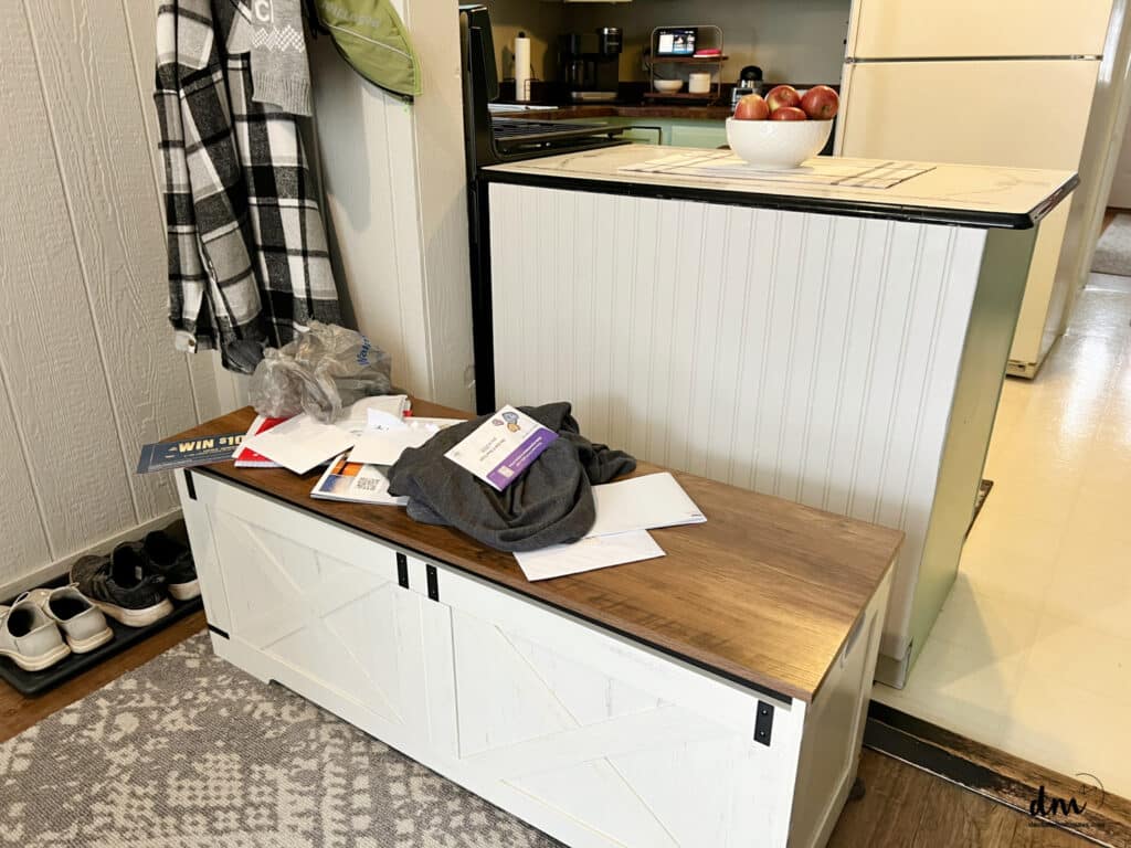 papers and clutter on a bench in a mudroom