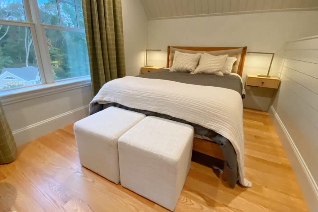 two storage ottomans at the foot of a bed in a cream and green bedroom